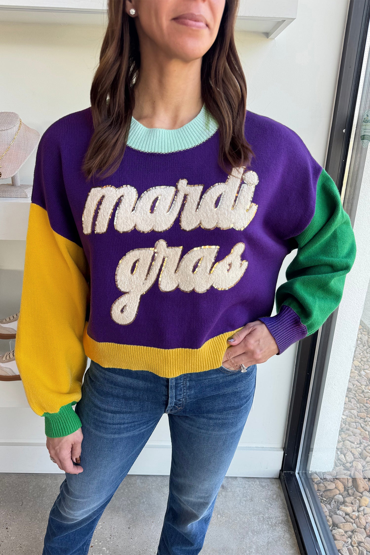 Woman wearing a colorful 'mardi gras' sweater with a green background